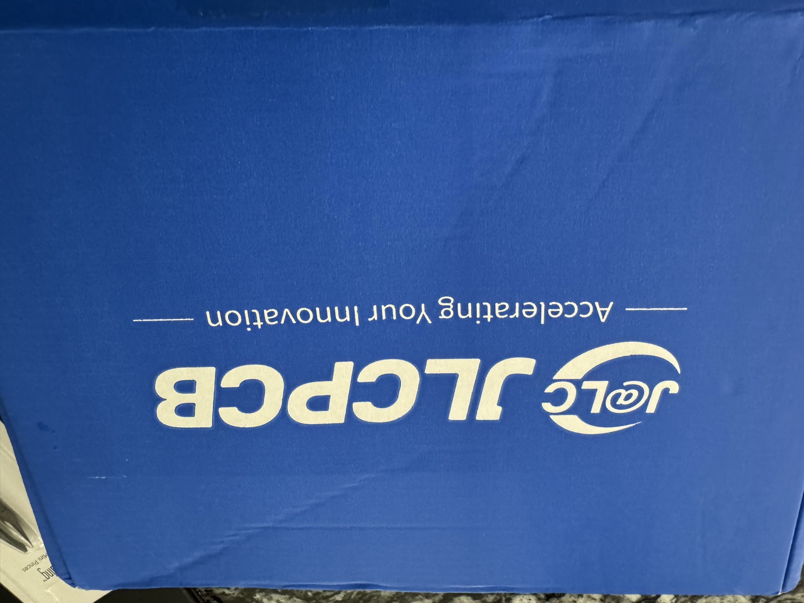 A blue JLCPCB shipping box on a kitchen counter
