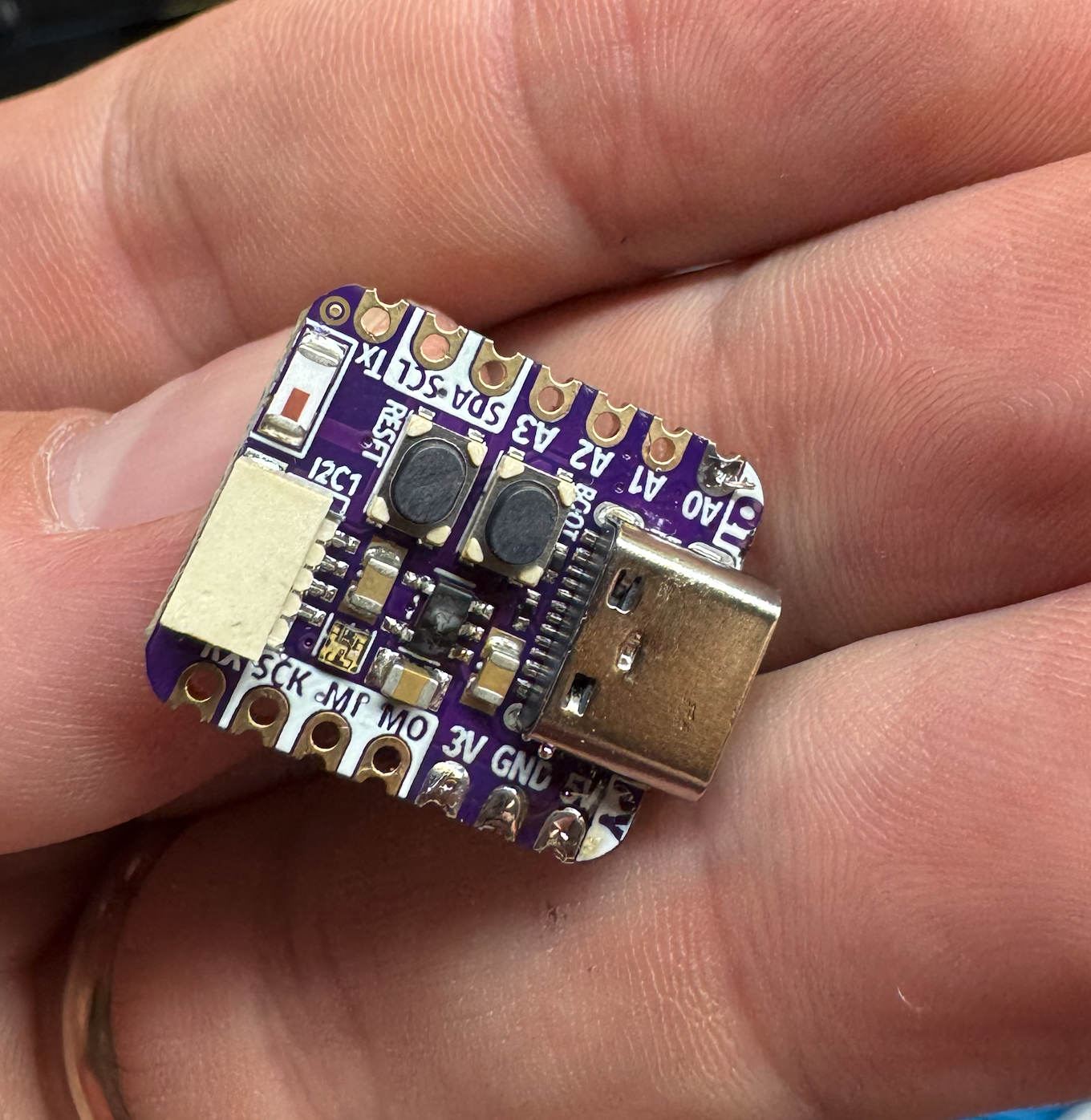 Dead QT Py ESP32-S3 held in hand, showing scorch marks